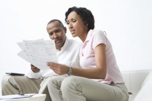 Couple looking at unpaid bills. Chapter 13 bankruptcy can allow you to reorganize your debts, establish a repayment plan that you can afford and get back on track financially.