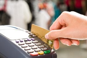 Hand sliding a gold credit card through a charge reader. Bankruptcy can be a solution to wipe out credit card debt that has spiraled out of control.