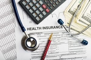 Health insurance forms and hundred dollar bills. if you have an HSA, FSA or HRA account, you may be concerned that filing for bankruptcy will put those accounts at risk.