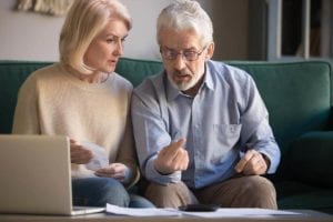 Concerned middle aged couple reviewing finances. It is not advisable to dip into retirement accounts to pay off debts.